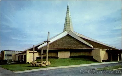 Exterior photo of former (newer) church. Note the three large crosses in the foreground. Source: Card Cow