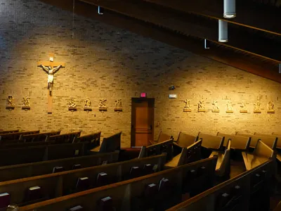 Right side of church with stations of the cross along the wall.