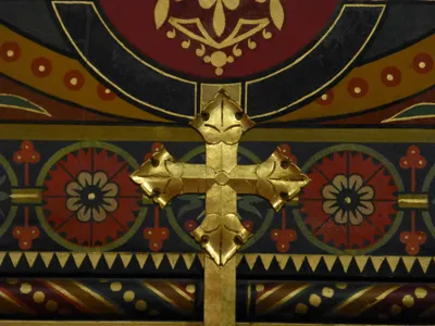 Engraved cross above stained glass windows.
