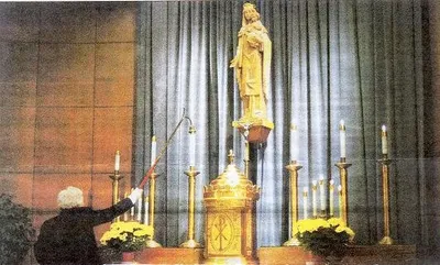 Woman extinquishes the candles during the final Mass. Source: Catholic Courier