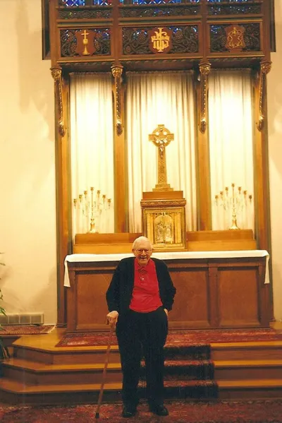 Msgr. Shannon standing in the sanctuary while the chapel was still used by the Rochester SSJs. High altar with tabernacle, crucifix, and candles still intact.