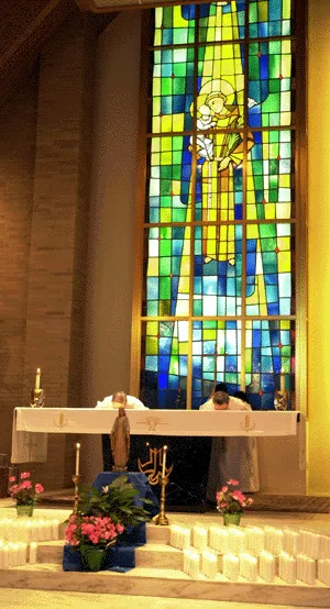 Altar and large back-lit stained glass window. Source: Catholic Courier