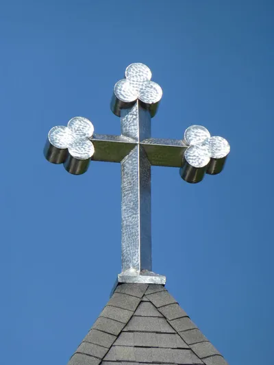 Large metal cross atop bell tower.