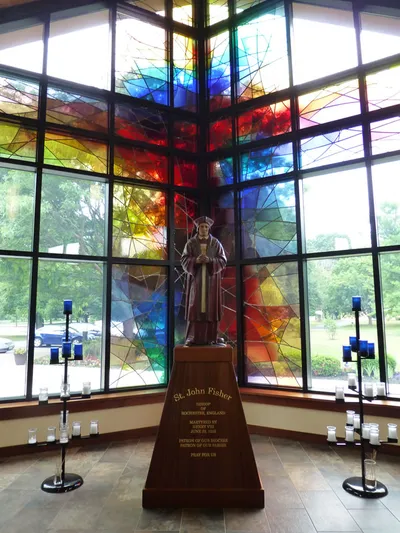 Shrine to St. John Fisher with stained glass windows behind.