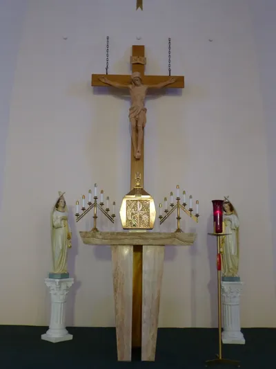 Crucifix, statues, and tabernacle behind altar.