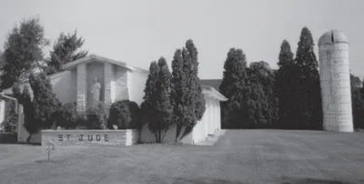 Exterior of original St. Jude campus. The building behind the statue of St. Jude served as the parish hall. The actual church is located behind the hues and next to the bell tower/silo.