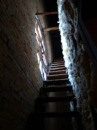 Stairs leading up to attic. Can see front rose window on left side.